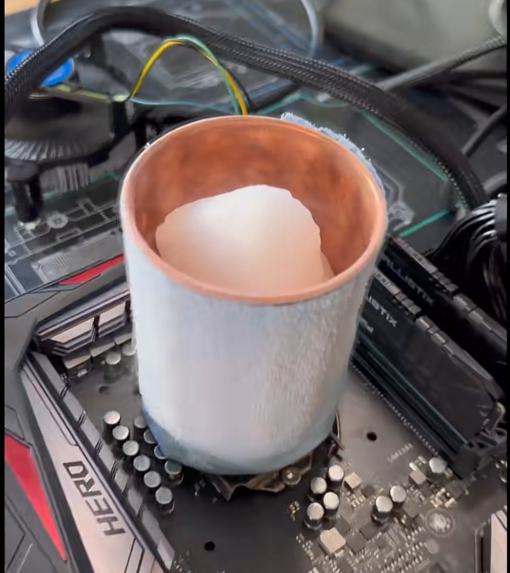 Frost-covered CPU cooling pot mounted on a motherboard with dry ice inside its copper-lined opening.