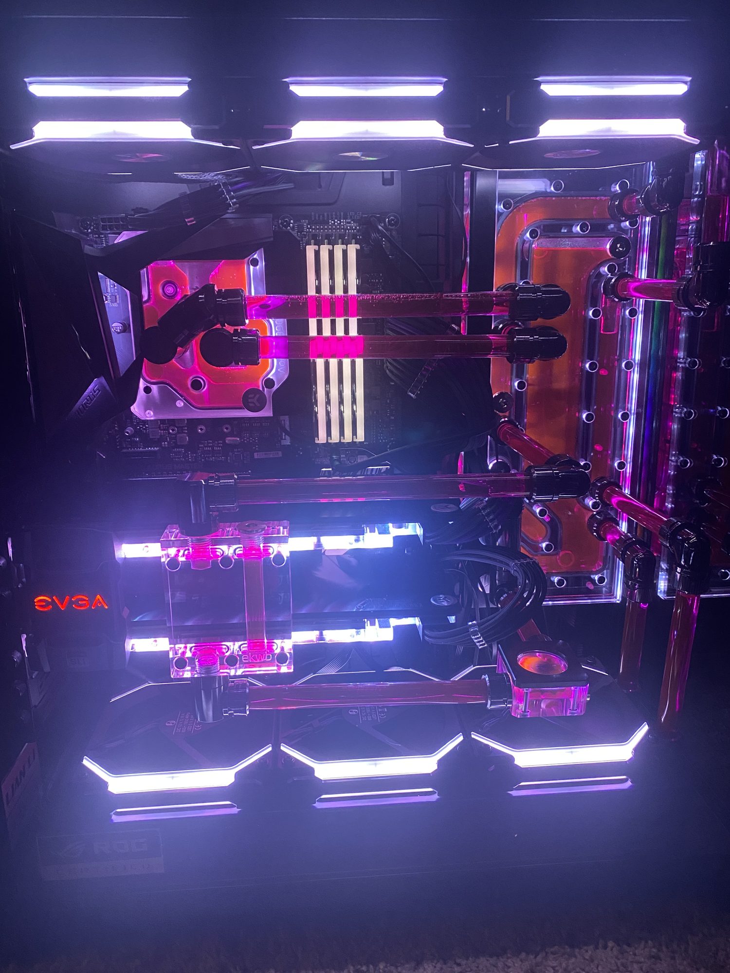 The same custom-loop PC illuminated by bright white fans around its red-pink coolant.