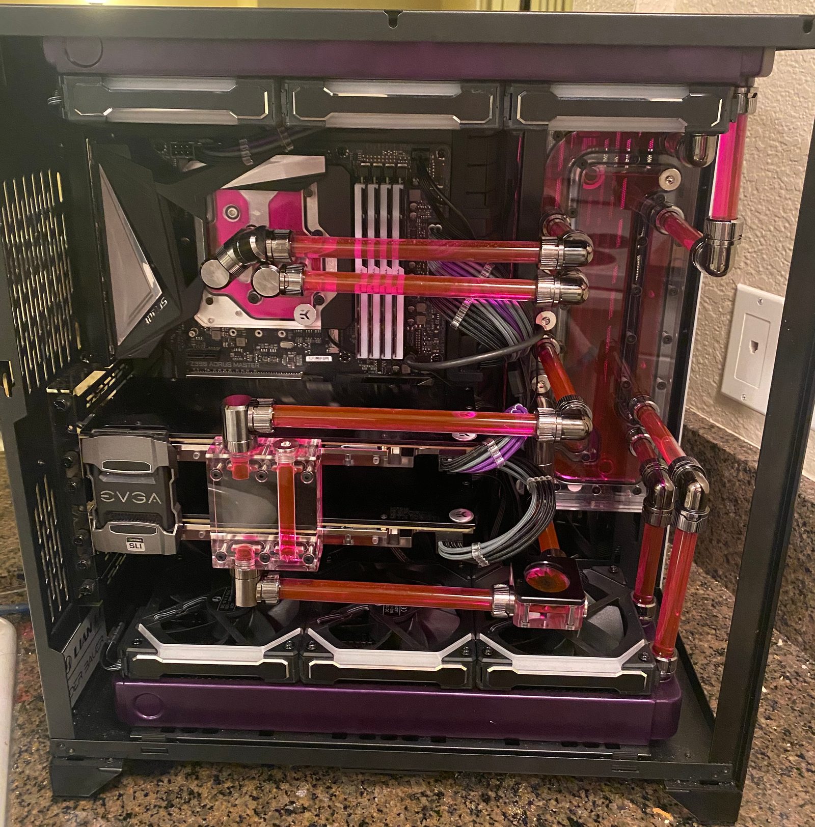 Open black desktop PC with a rigid-tube cooling loop filled with red-pink coolant.